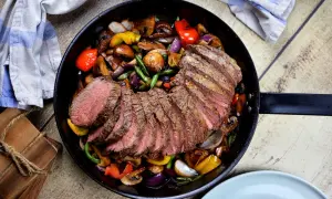 Skivad rostbiff med perfekt rostas innertemp, serverad med sauterade grönsaker i en gjutjärnspanna.