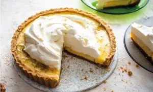 En krämig key lime pie med fluffig grädde på toppen, en bit serverad på en grön tallrik.
