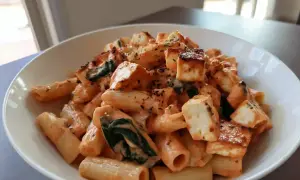 En skål med krämig halloumi pasta med spenat och kryddor.