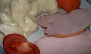 En tallrik med stuvad blomkål, skinka, en morot och en tomatklyfta. En klassisk svensk husmansrätt.