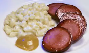En tallrik med krämiga stuvade makaroner, skivad falukorv och en klick senap. En klassisk svensk rätt som väcker barndomsminnen.