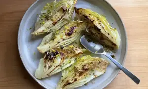 Grilla spetskål med citron och örter, serverad på en ljusgrå tallrik med en sked.