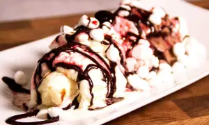 En läcker banana split med tre kulor glass, chokladsås, marshmallows och körsbär.