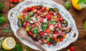 En härlig somrig sallad med jordgubbar, vattenmelon, tomater och basilika på ett vackert fat.
