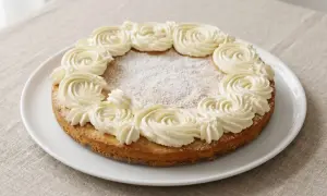 En härlig semmelkladdkaka glutenfri med fluffig grädde runt kanten, pudrad med florsocker.