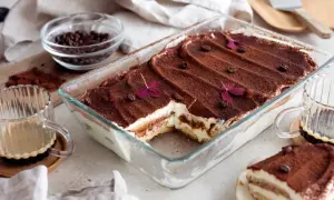 En härlig tiramisu i glasform, pudrad med kakao och dekorerad med kaffebönor och blommor. Perfekt för tips på bakning!