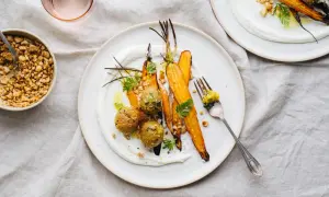 En tallrik med ugnsrostade morötter, gröna bollar och krämig sås. En perfekt somrig mat-upplevelse med krispiga nötter som topping.