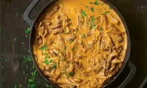 En krämig biff stroganoff i en gjutjärnspanna, toppad med färsk persilja.