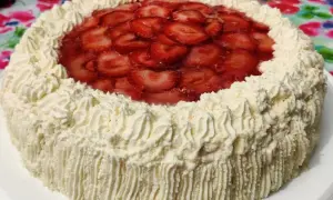 En vacker tårta med fluffig grädde och ett glansigt lager av färska jordgubbar. Perfekt för sommarens firanden!