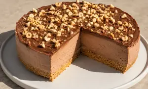 En krämig nutella cheesecake med chokladglasyr och rostade hasselnötter. En bit är bortskuren.