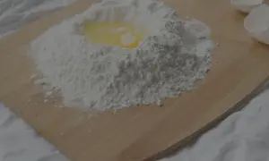 Mjöl och ett ägg ligger på en skärbräda, redo att blandas. Kanske för en kaka eller pannkakor, där bikarbonat och bakpulver kan komma till användning.