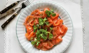 Vacker tallrik med gravad lax, garnerad med dill och gröna blad. Frågan är om man kan frysa gravad lax för att spara den till senare.