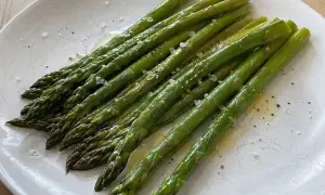 En tallrik med perfekt kokt sparris, strödd med flingsalt och nymalen svartpeppar. Enkel och god matlagning.