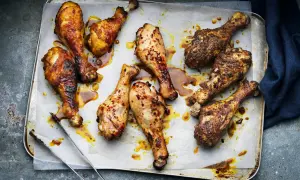 Nio saftiga kycklingben, vissa kryddade med chili, ligger på en plåt. Perfekt innertemp kycklingben för en härlig måltid.