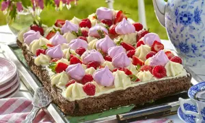 En chokladkaka i långpanna, dekorerad med grädde, maränger och färska bär. Perfekt för ett sommarfika.
