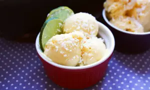 Krämig kvarg glass med kokosflingor och lime i en röd skål. En perfekt sommardessert!