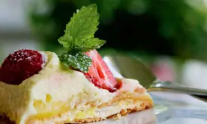 En bit pavlova med lemoncurd, toppad med färska jordgubbar och mynta. En härlig sommardessert.