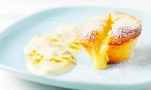 En ljuvlig vit chokladfondant med smältande fyllning, serverad med passionsfruktsås på en ljusblå tallrik.