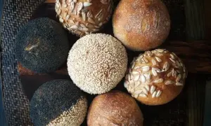 En samling nybakade surdegsbröd, några toppade med vallmofrön, sesamfrön och solrosfrön. Perfekt för att starta surdeg råg.