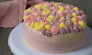 En vacker tårta med rosa, lila och gula frostingrosor. Denna tårta är perfekt för att spritsa tårta till ett speciellt tillfälle.