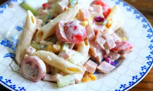 En krämig pastasallad med skinka, penne, körsbärstomater, gurka och majs. Perfekt för en snabb och god lunch.