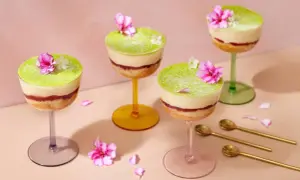 Fyra vackra prinsesstårtor i glas, dekorerade med blommor och strösocker. Perfekt för en festlig fika.
