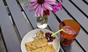 En tallrik med kex med jordnötssmör, nötter och torkade tranbär, samt ett glas smoothie. Perfekt för ett snabbt och gott mellis tips.