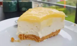 En krämig bit citron cheesecake med krispig botten, redo att avnjutas.
