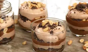 Chokladmousse-desserter i glas med lager av choklad, kolasås och jordnötter. En härlig rocky road-upplevelse!