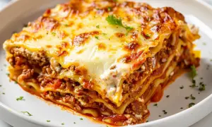 En saftig bit lasagne med gyllene ost och köttfärssås, redo att avnjutas. Perfekt lasagne tid i ugn!