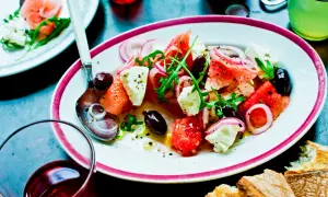 En läcker melon och fetaostsallad med oliver, rödlök och ruccola. Serveras med bröd och en kall dryck.
