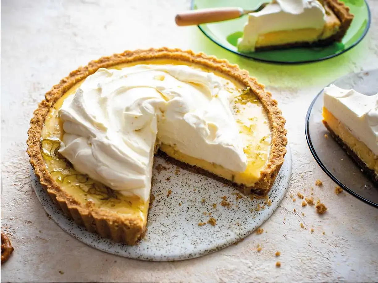 En krämig key lime pie med fluffig grädde på toppen, en bit serverad på en grön tallrik.