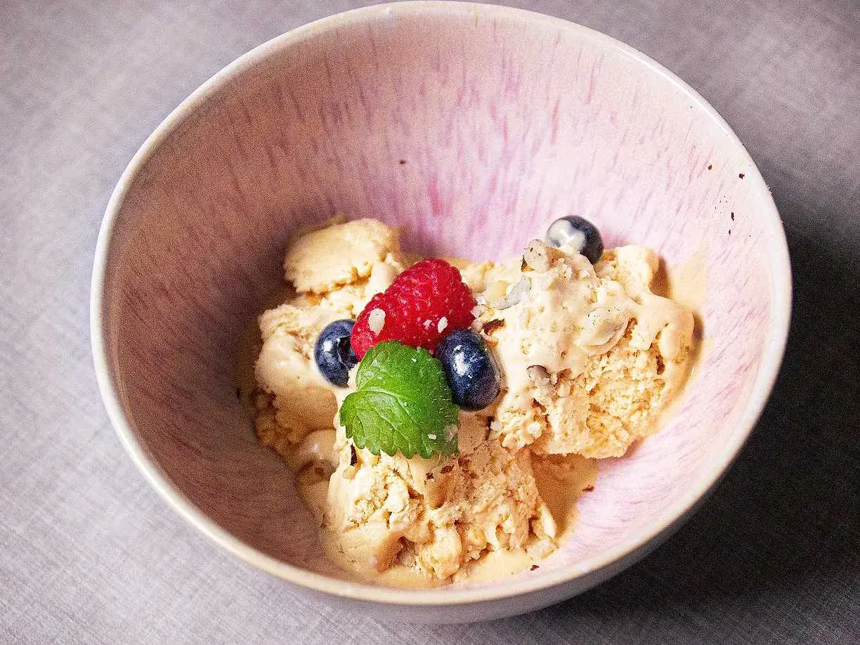 En skål med krämig dulce de leche glass, toppad med färska bär och mynta. En härlig dessert som smälter i munnen.