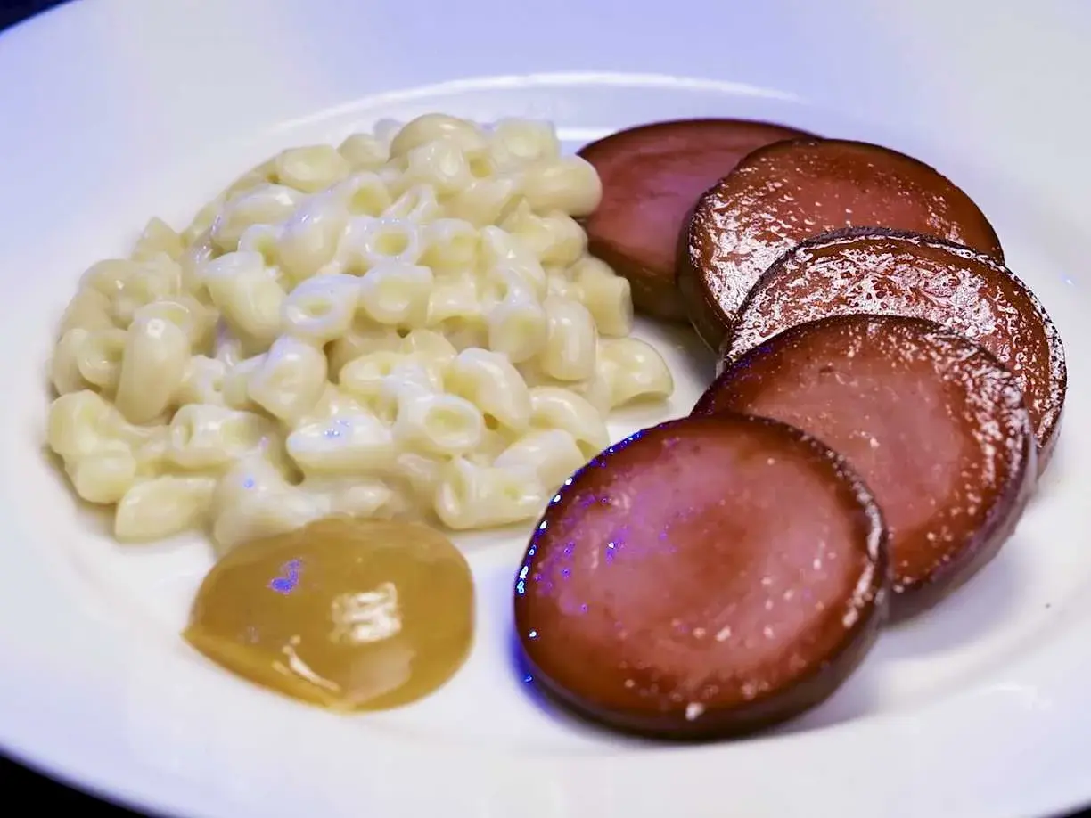 En tallrik med krämiga stuvade makaroner, skivad falukorv och en klick senap. En klassisk svensk rätt som väcker barndomsminnen.