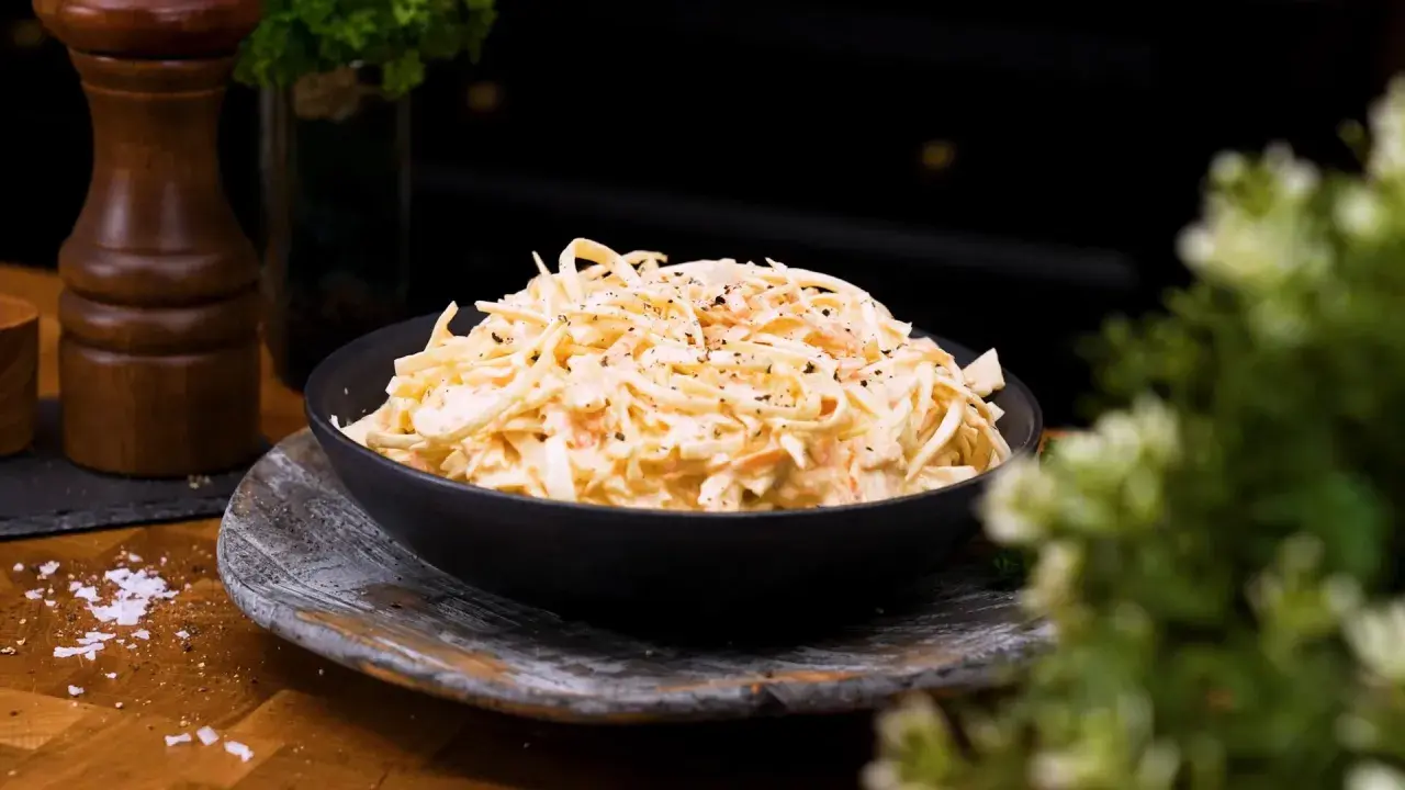 En skål med krämig, godaste coleslaw, toppad med nymalen svartpeppar. Perfekt tillbehör!