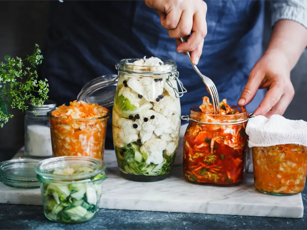 Här är flera burkar med fermenterad mat, inklusive surkål och kimchi, redo att avnjutas.