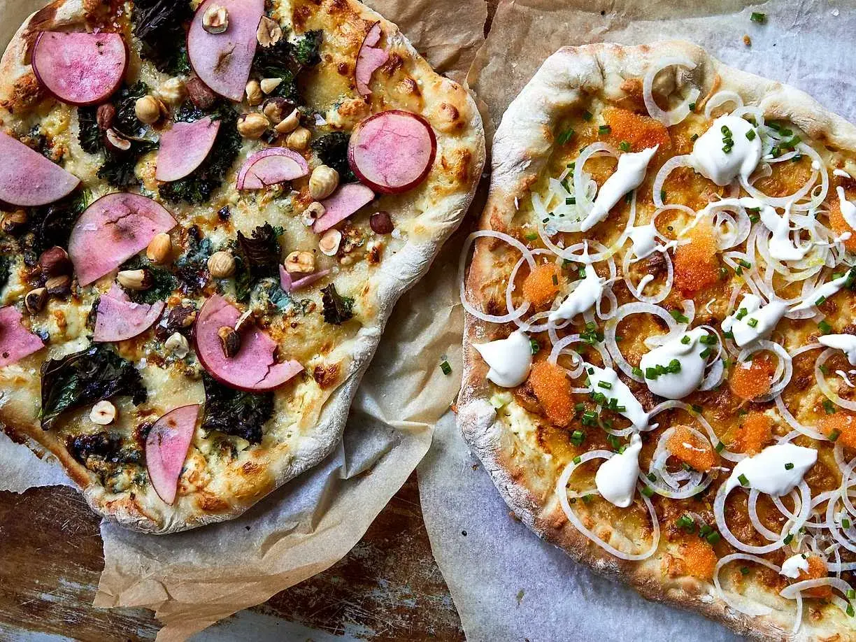 Två pizzor med egen pizza topping. En med äpple, nötter och grönkål, den andra med rom, lök och gräddfil.