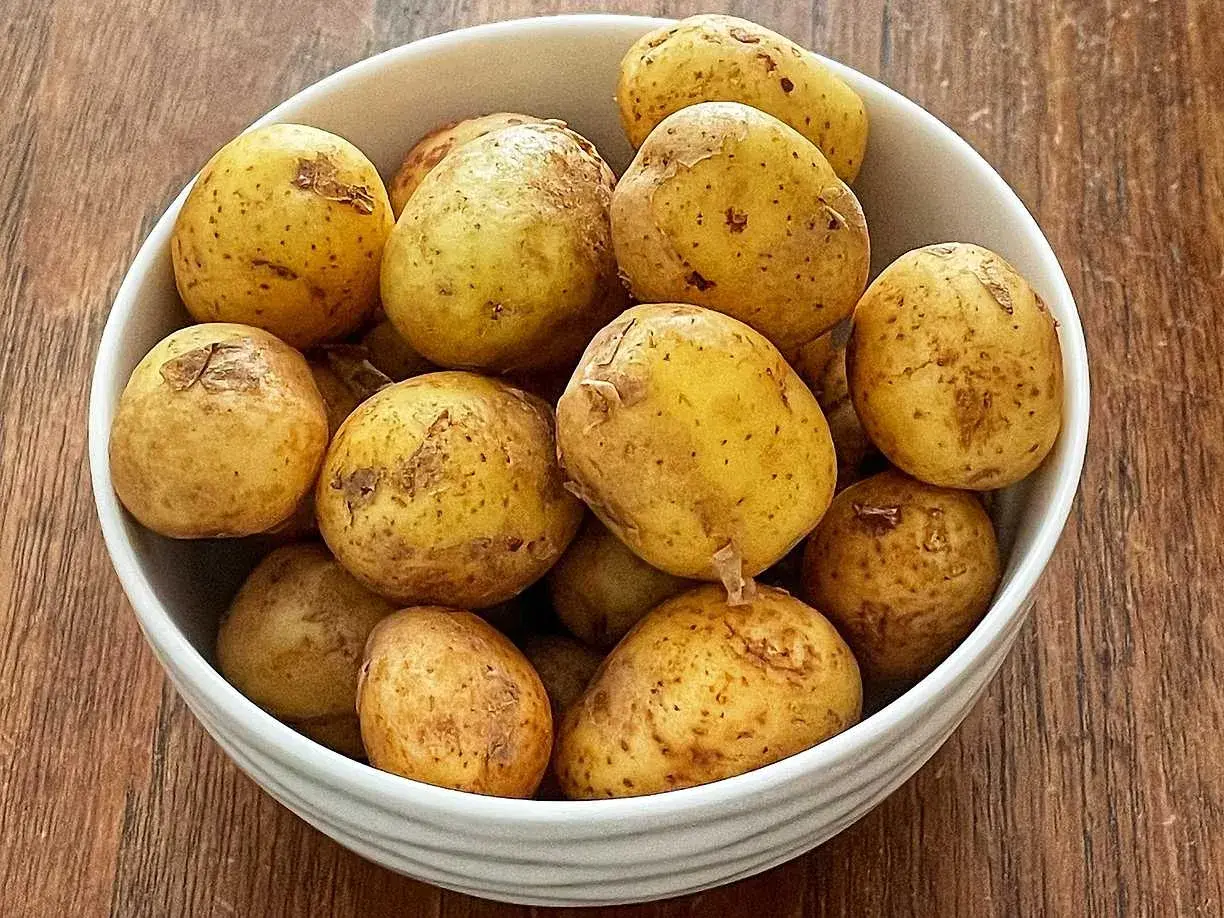 En skål med färskpotatis, redo att koka. Perfekt för en svensk sommarmåltid.
