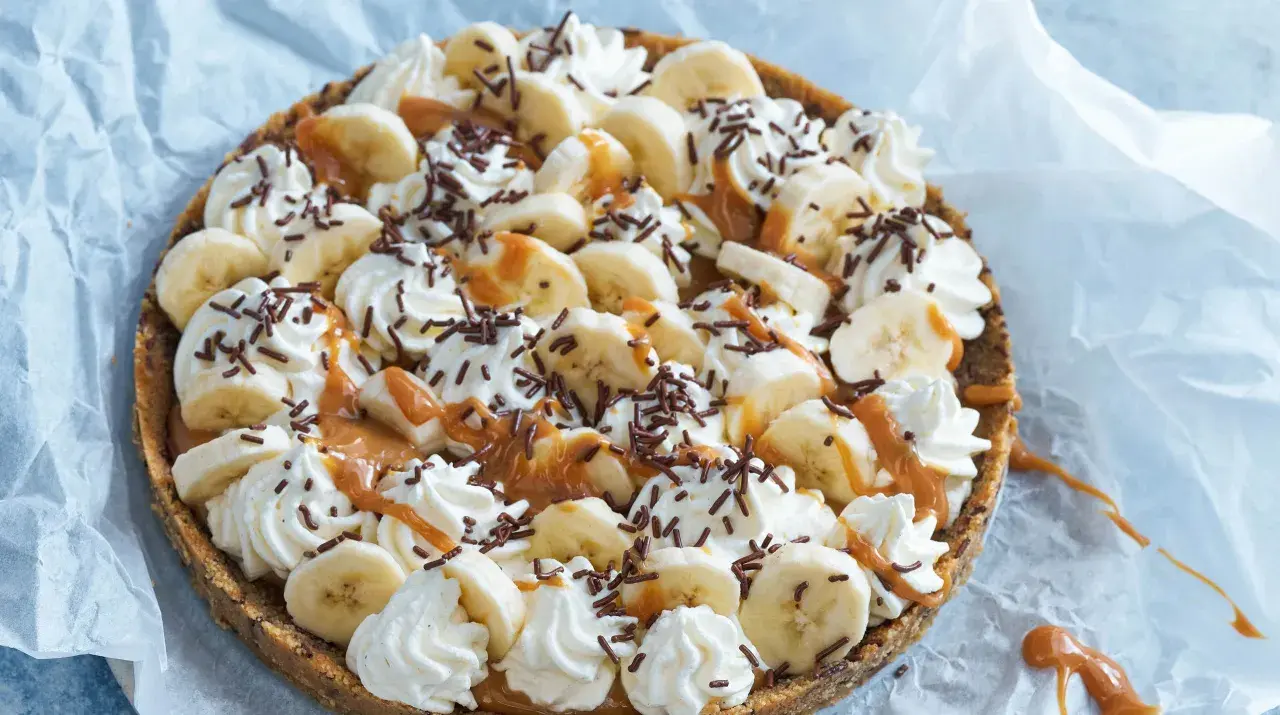 En läcker banoffee paj i glas, toppad med bananskivor, vispgrädde, kolasås och chokladströssel. Perfekt för en fika!