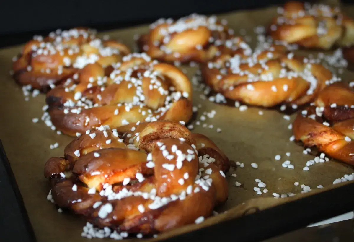 Nybakade kanelbullar med pärlsocker, redo för kanelbulle dag. Doften sprider sig i köket.
