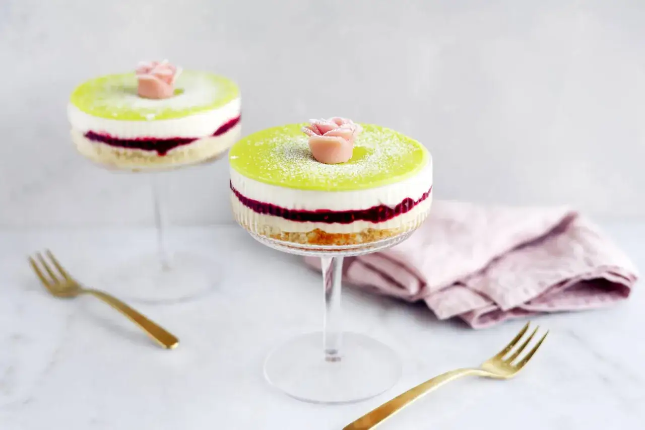 Två eleganta prinsesstårtor i glas, dekorerade med en rosa marsipanros och pudrade med florsocker. En festlig dessert!