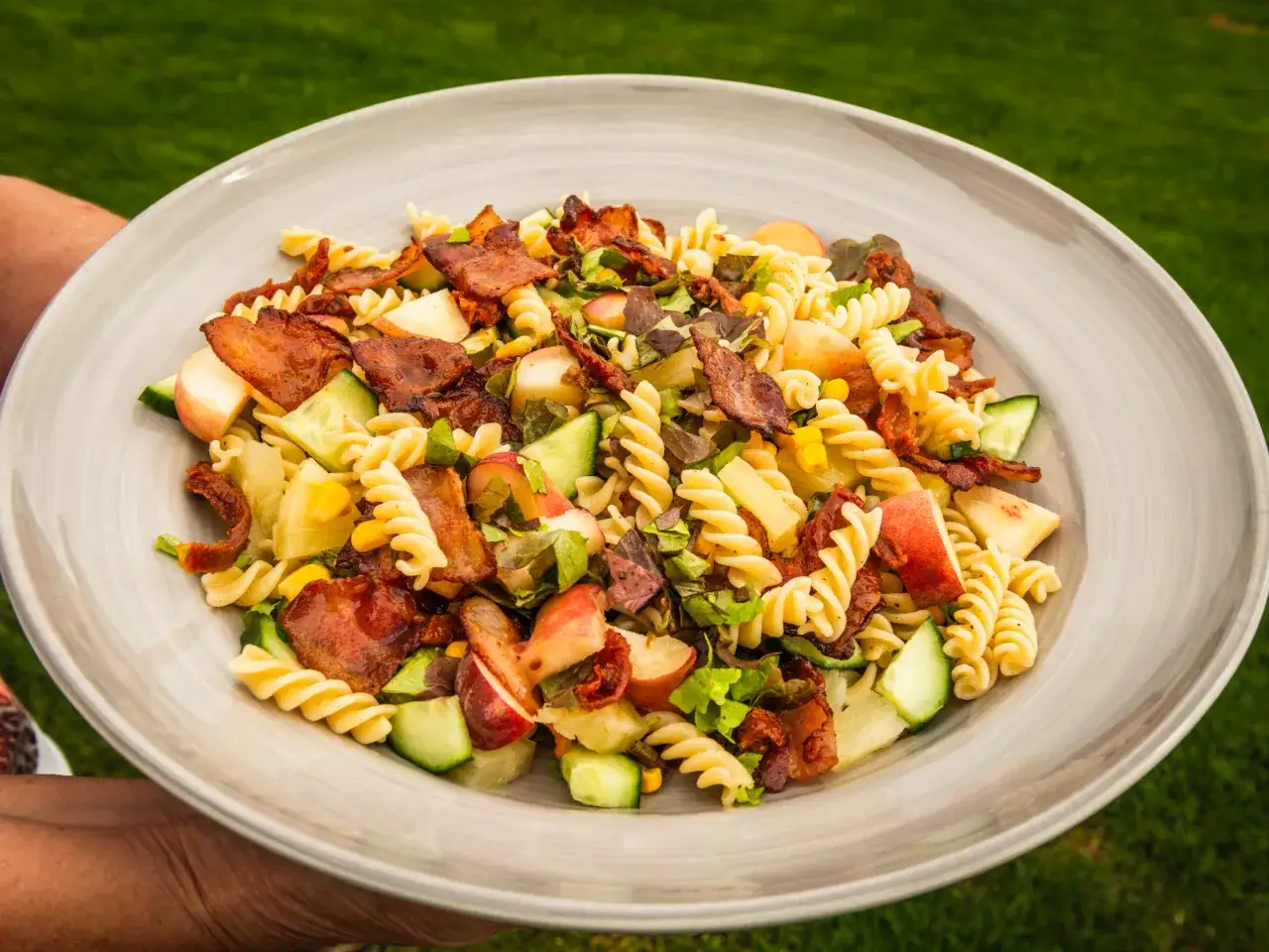 En härlig pastasallad med krispig bacon, gurka, äpple och soltorkade tomater. En perfekt pastasallad med bacon och fetaost för sommaren.