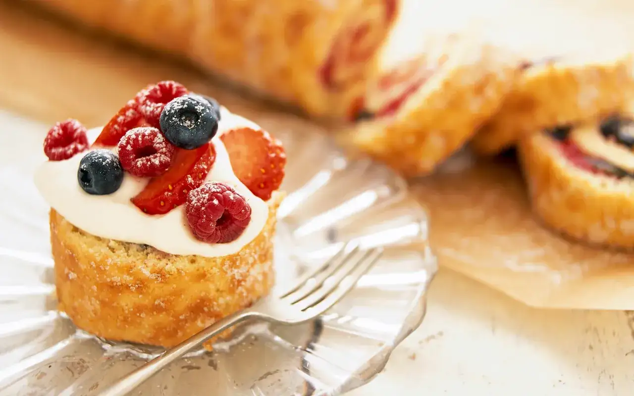 En glutenfri rulltårta med vispgrädde och färska bär, perfekt för en fika.
