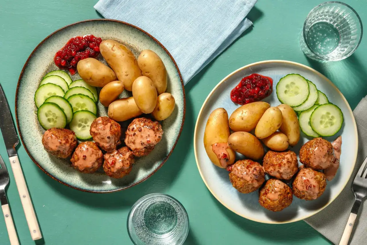 Två tallrikar med köttbullar, potatis, gurka och lingonsylt. Enkel och god mat som ger spartips för matbudgeten.