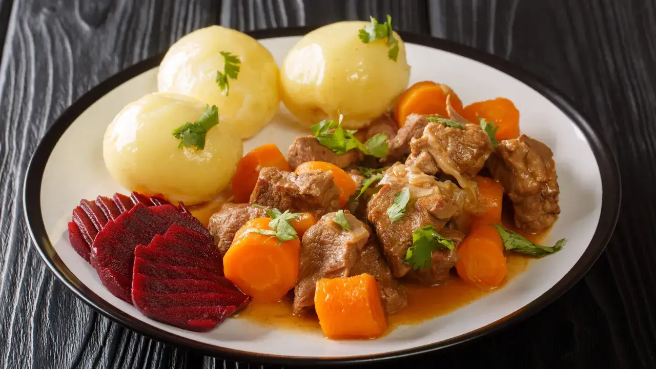 En tallrik med traditionell svensk mat: köttgryta med morötter, potatis och rödbetor.