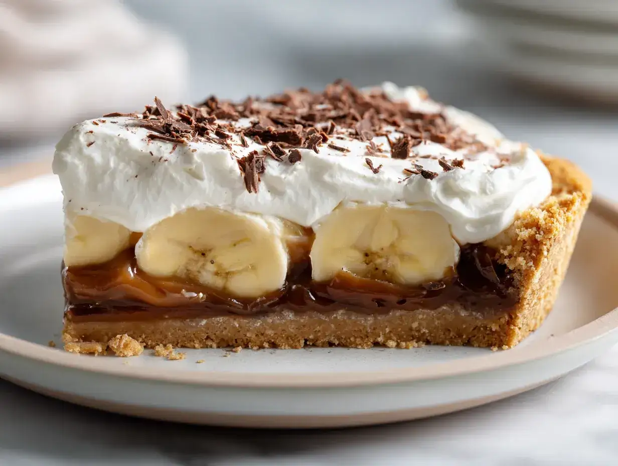 En bit banoffee paj med fluffig grädde, banan, kolasås och chokladströssel.