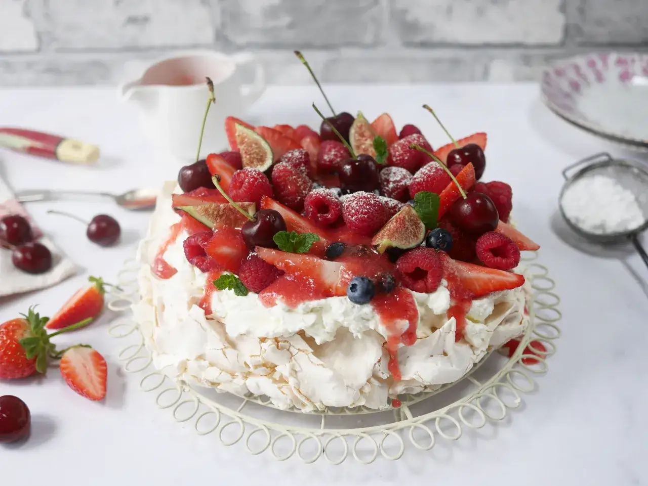 En härlig pavlova tårta med vispgrädde och massor av färska bär och frukter som jordgubbar, hallon, körsbär och fikon.