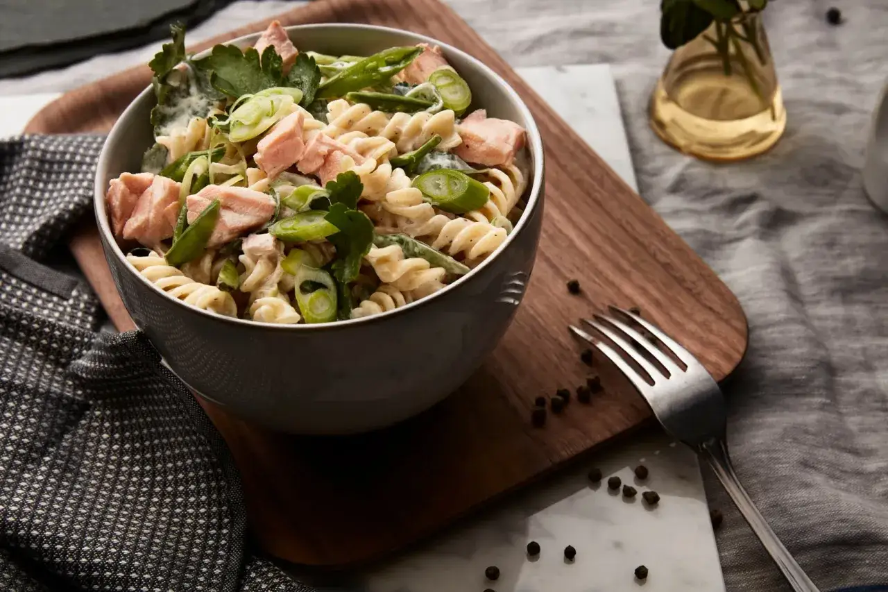 En krämig pastasallad med lax och fetaost, toppad med färska örter och salladslök. En perfekt sommarrätt!