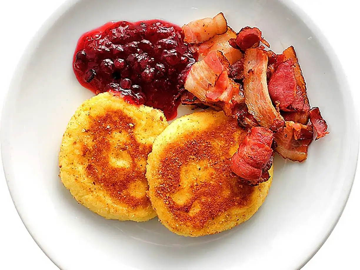 Två gyllene potatisbullar i airfryer serveras med lingonsylt och knaperstekt bacon.