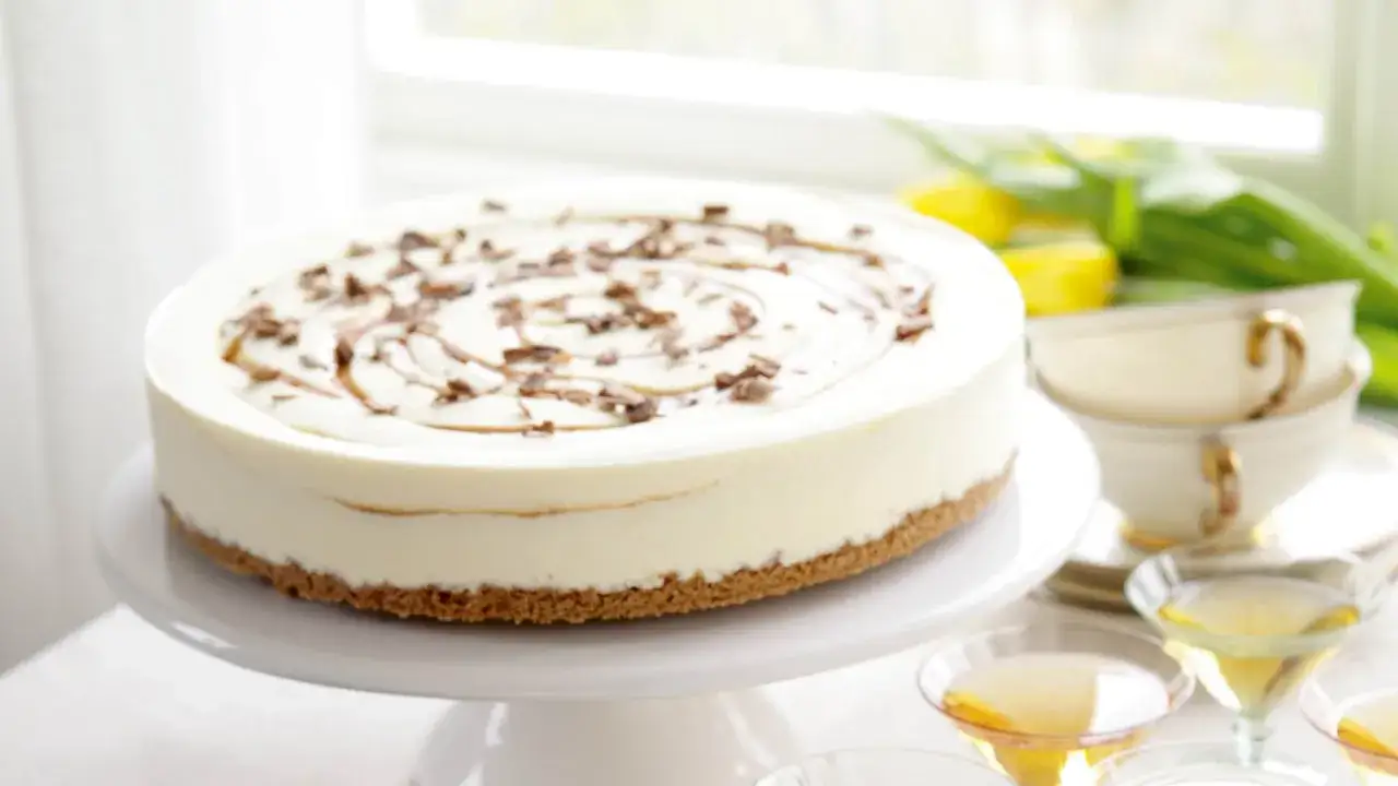 En krämig cheesecake med chokladströssel och en virvel av dulce de leche. Serveras med tekoppar och drinkglas.
